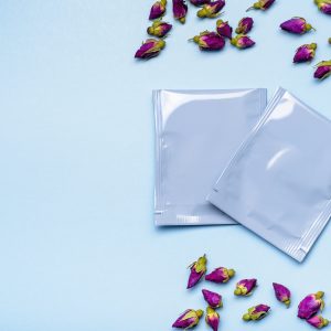 Two blue plastic tea bag sachets or envelopes with dry rosebuds.